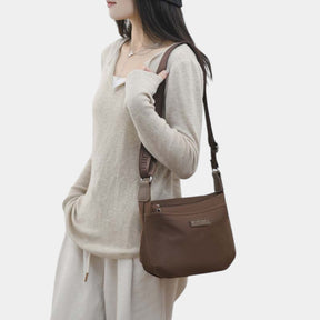Anti-theft crossbody travel bag for women in waterproof fabric with wide strap, top zipper, and multiple compartments for secure travel.