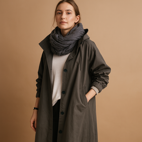 Women’s long waterproof raincoat with hood and belt, ideal for staying dry and stylish in all weather conditions.